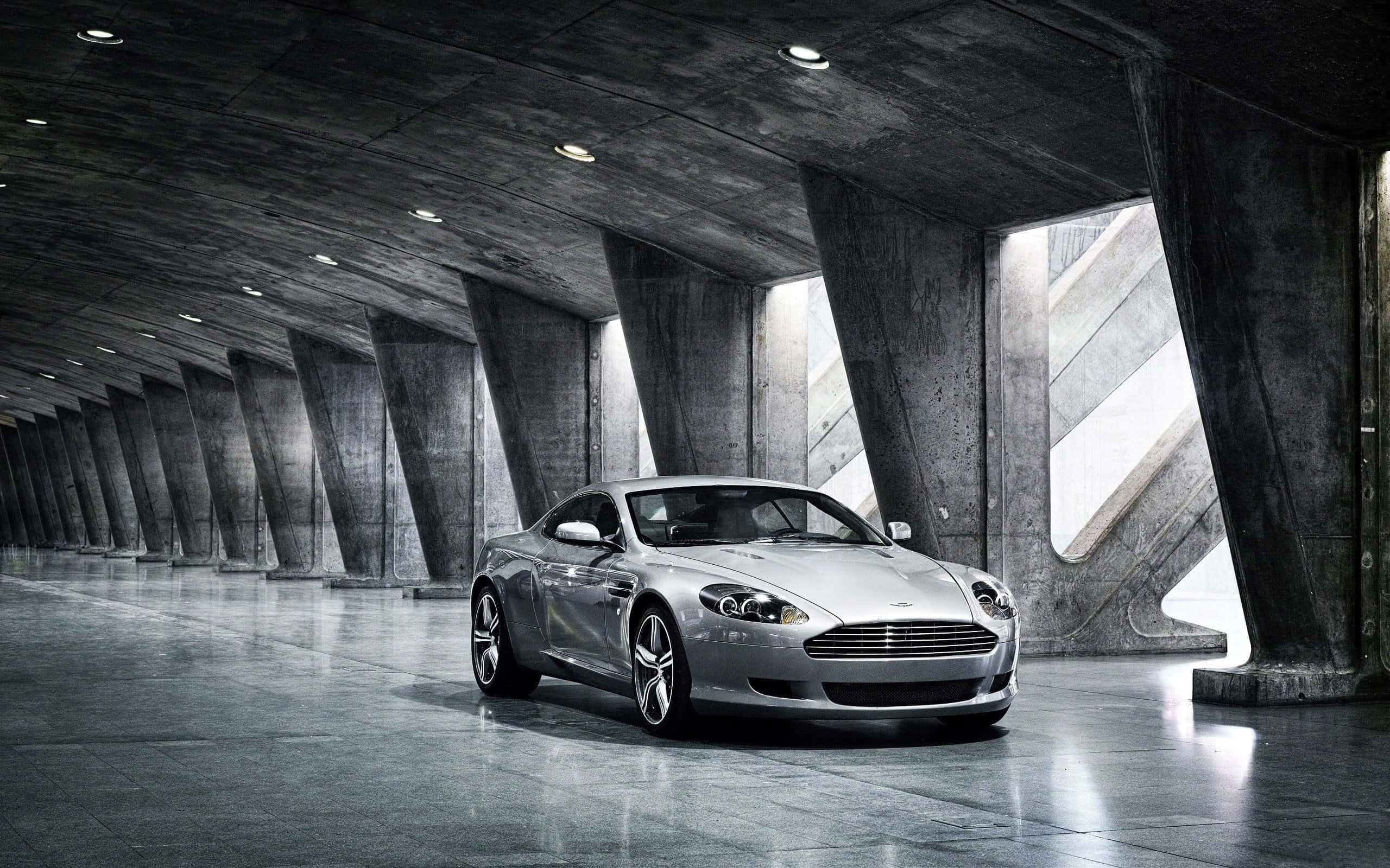 Aston Martin DB9, проезжающий по живописному городскому пейзажу Шпалери
