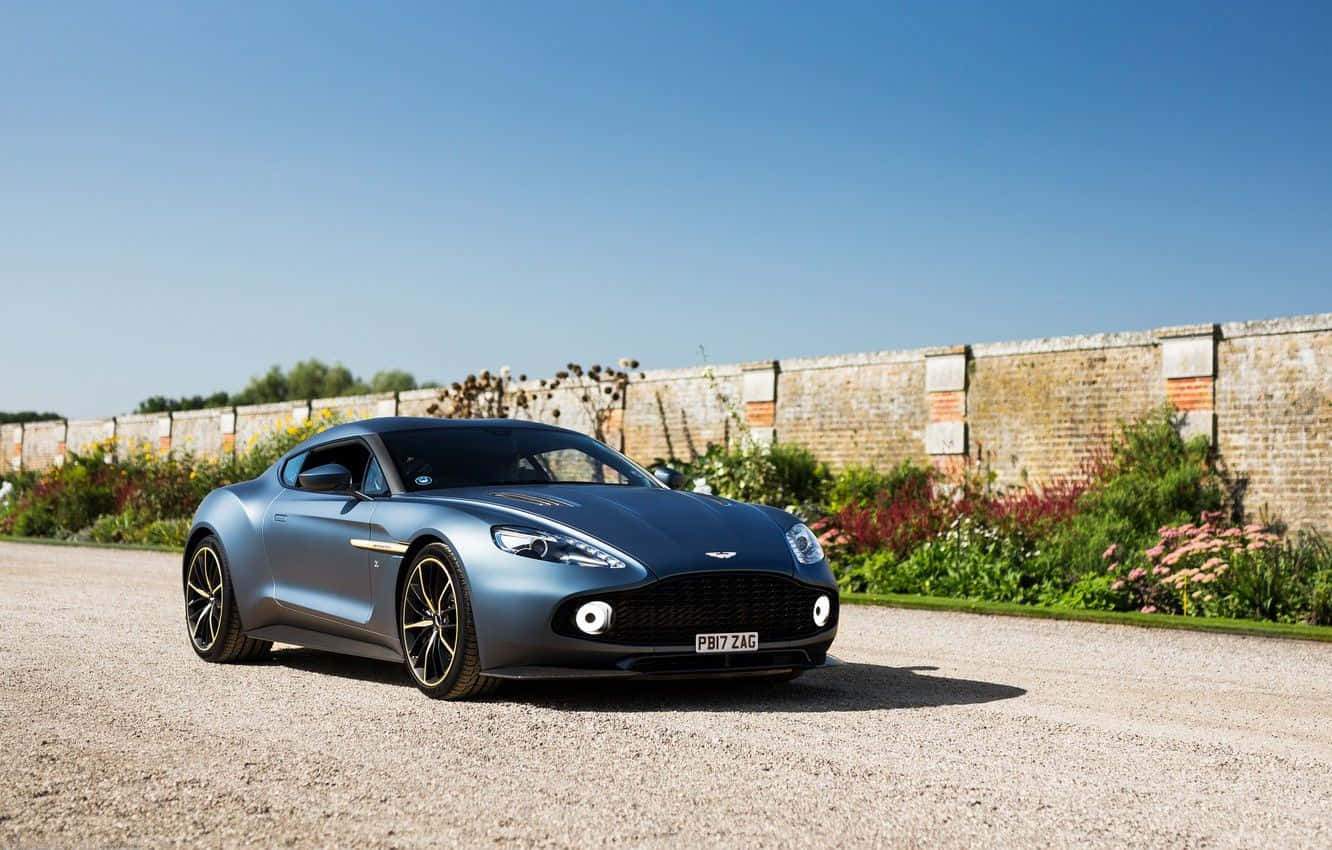 Потрясающий Aston Martin Vanquish в движении на живописной дороге Шпалери