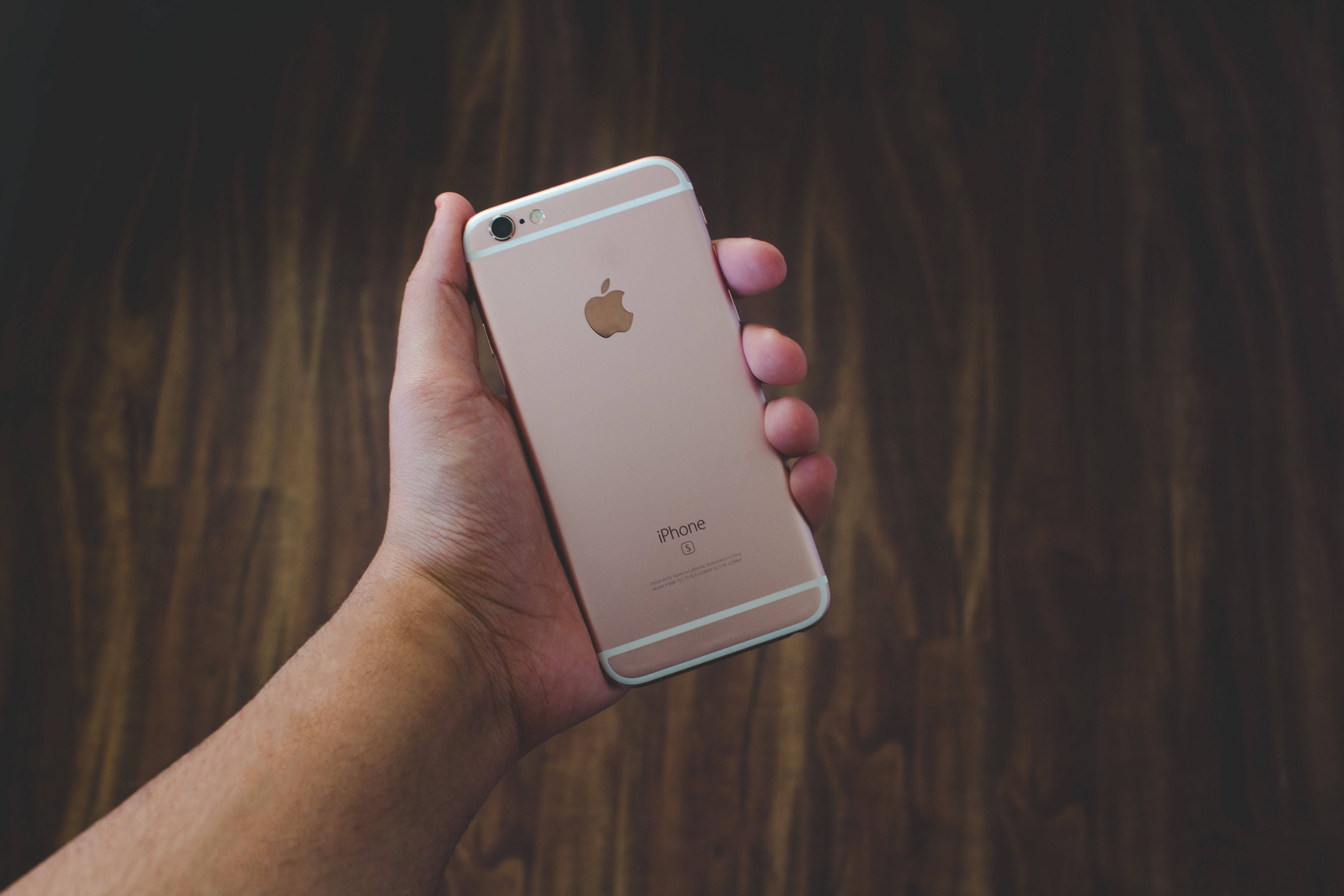 Рука, що тримає iPhone 6 рожевого золота Шпалери
