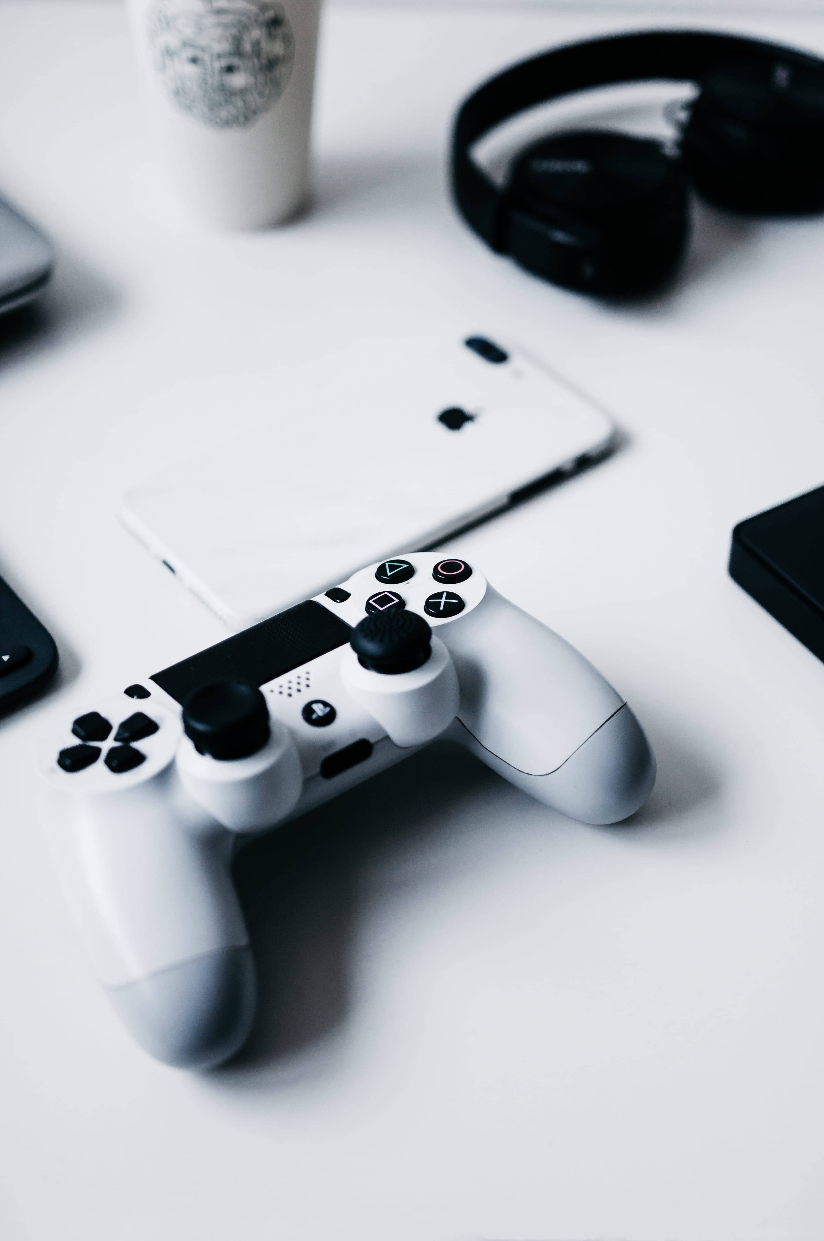 iPhone на столі с геймпадом PlayStation Шпалери