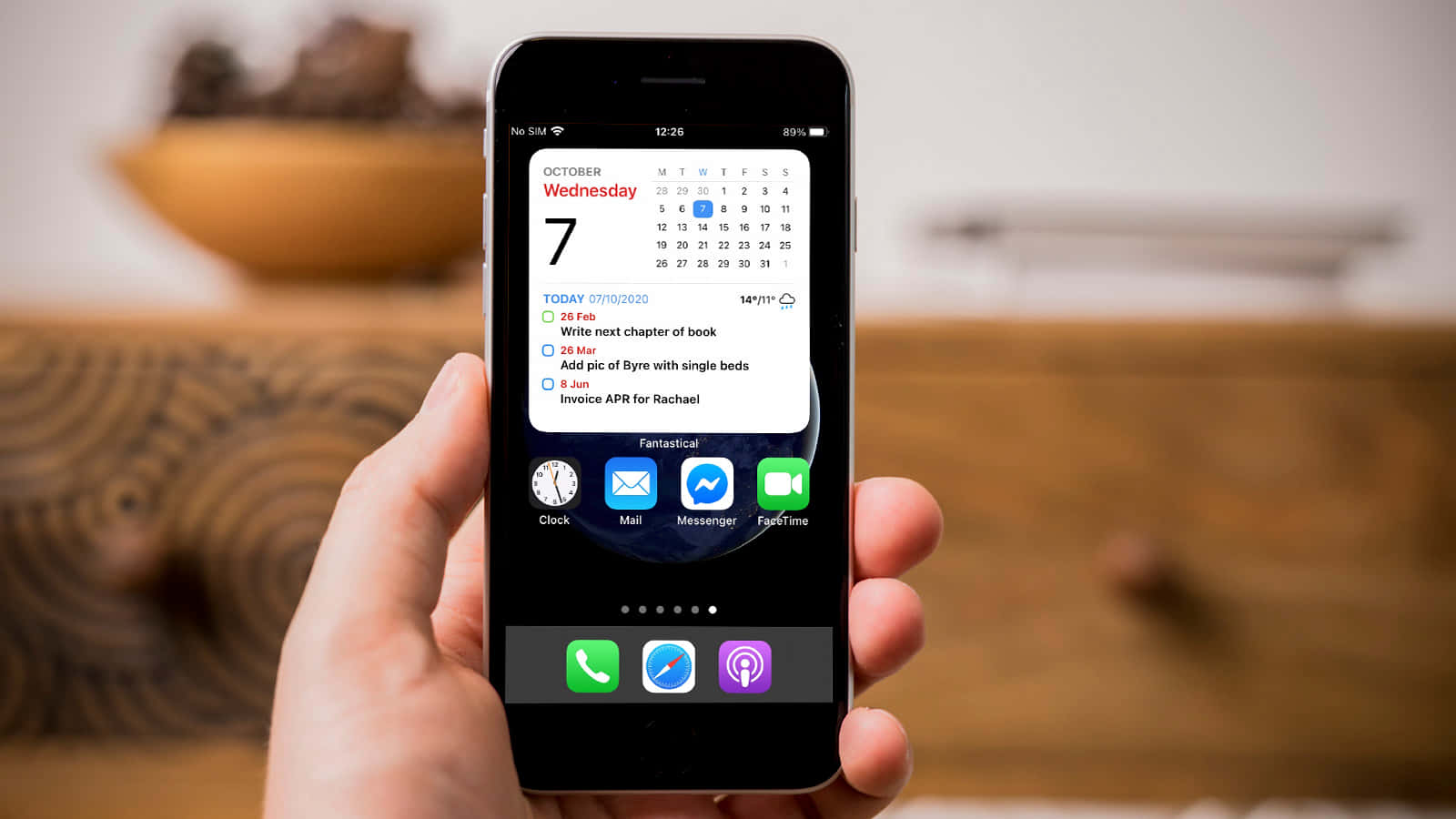 людина тримає iPhone з календарем на екрані Шпалери