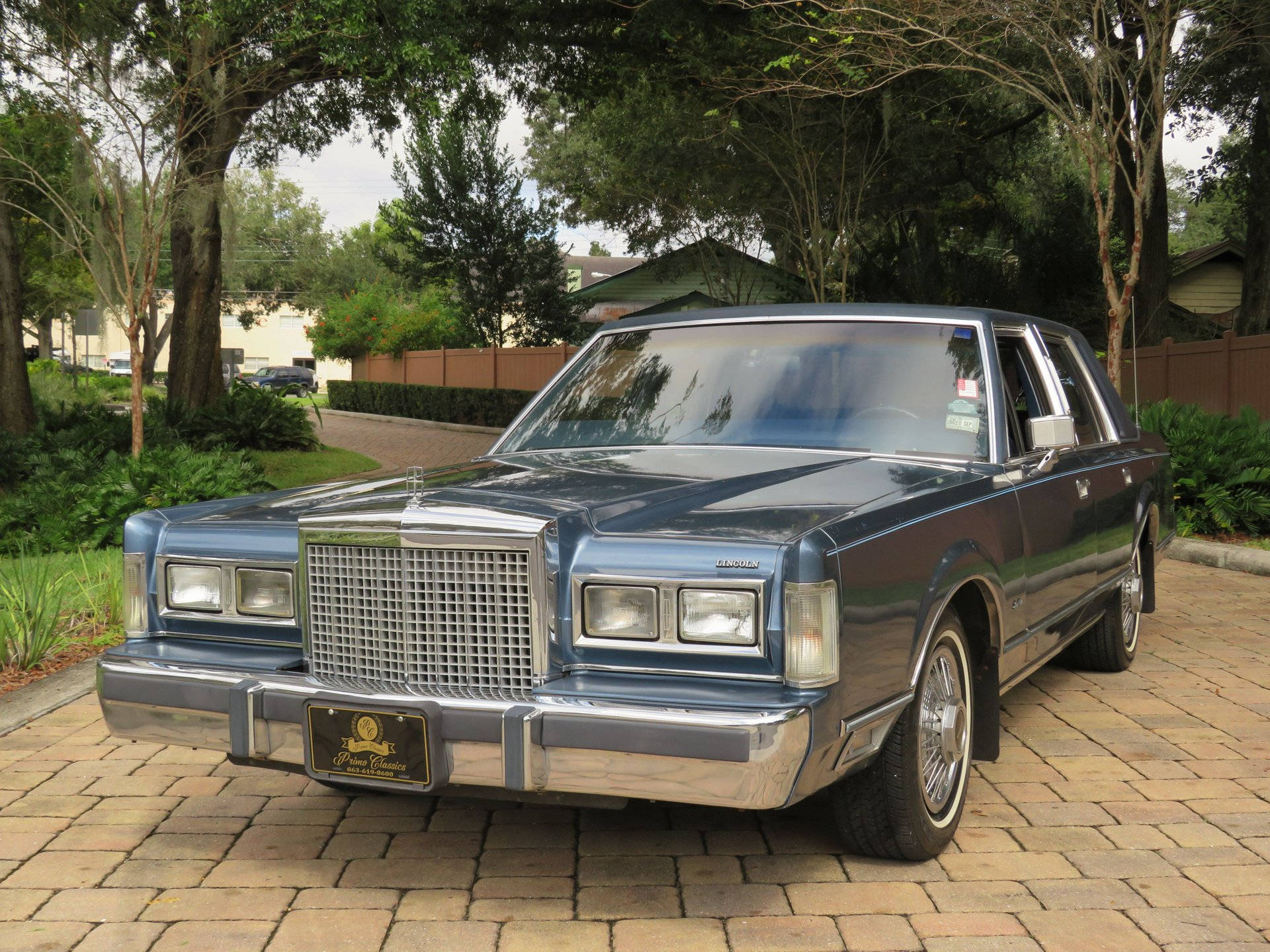 Величественный Lincoln Town Car 1986 года на асфальтированной подъездной дорожке Шпалери