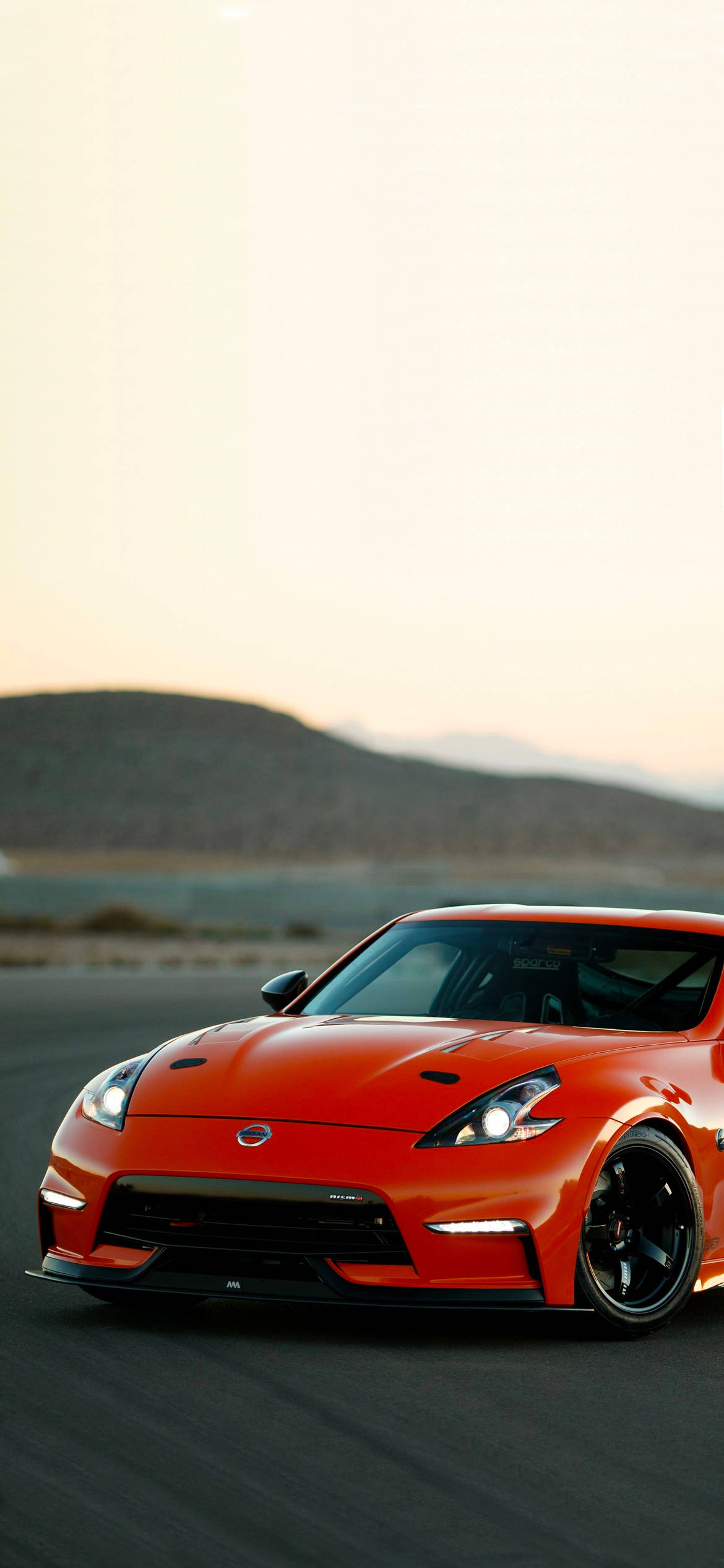 Красный Nissan 370Z на фоне холма Шпалери