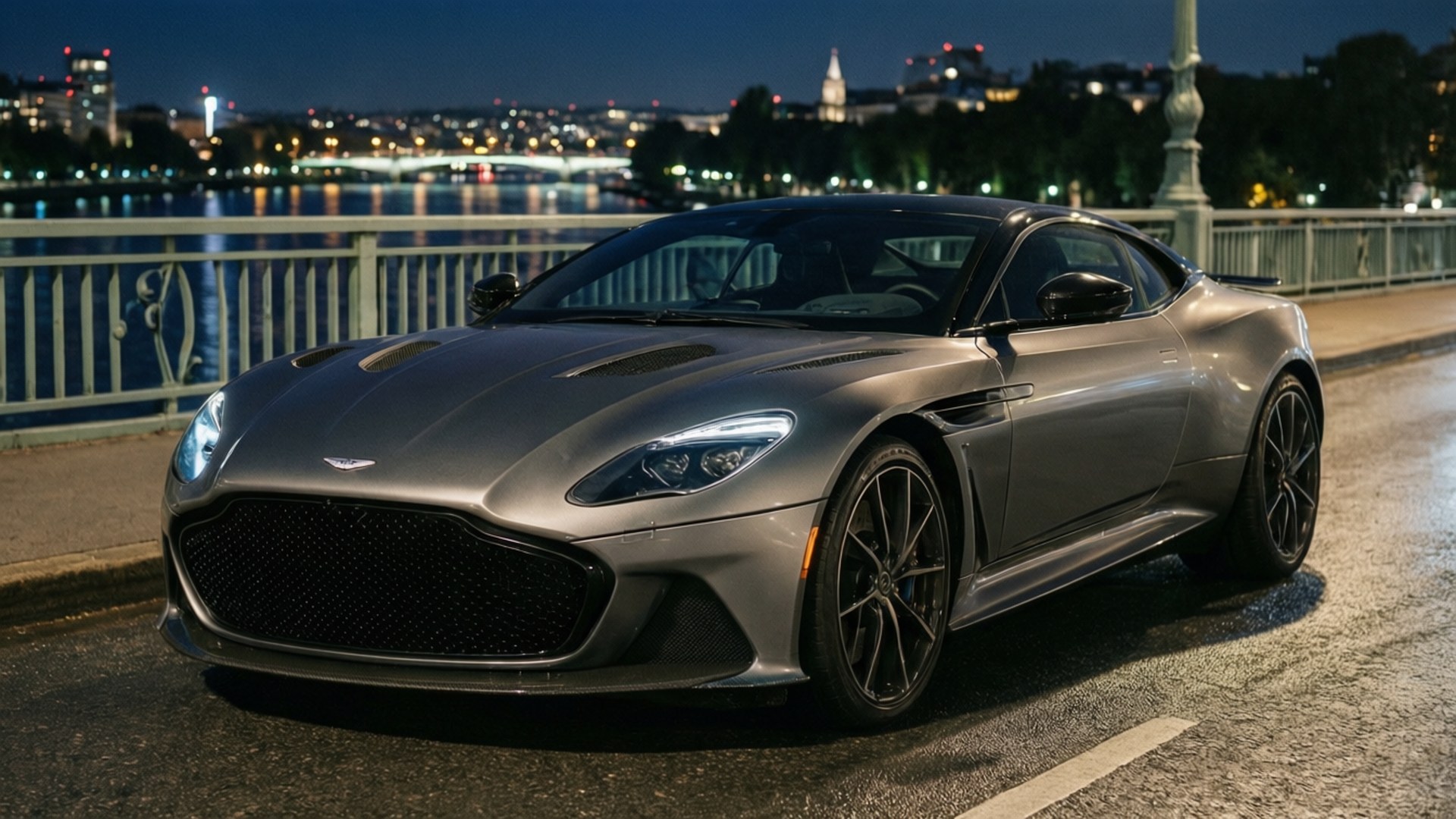 Aston Martin DBS Superleggera на мосту вночі з вогнями міста.