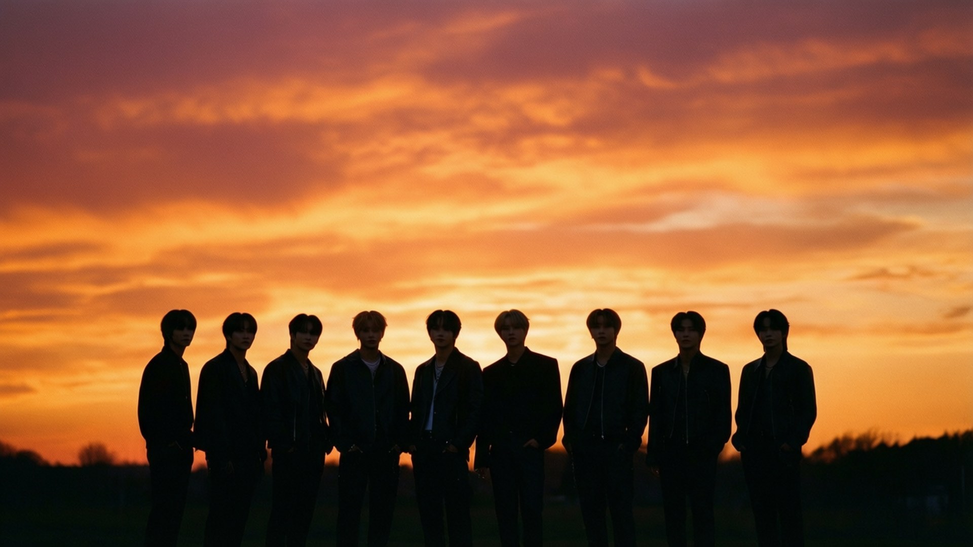 Силуети учасників Stray Kids на тлі барвистого заходу сонця