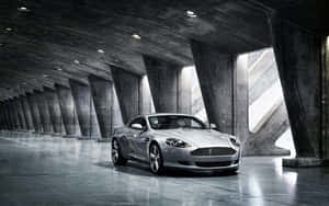Aston Martin DB9, проезжающий по живописному городскому пейзажу — Steam Deck OLED Шпалери