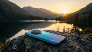 Телефон Huawei на камені, що виходить на горное озеро на закаті, спокойный пейзаж.